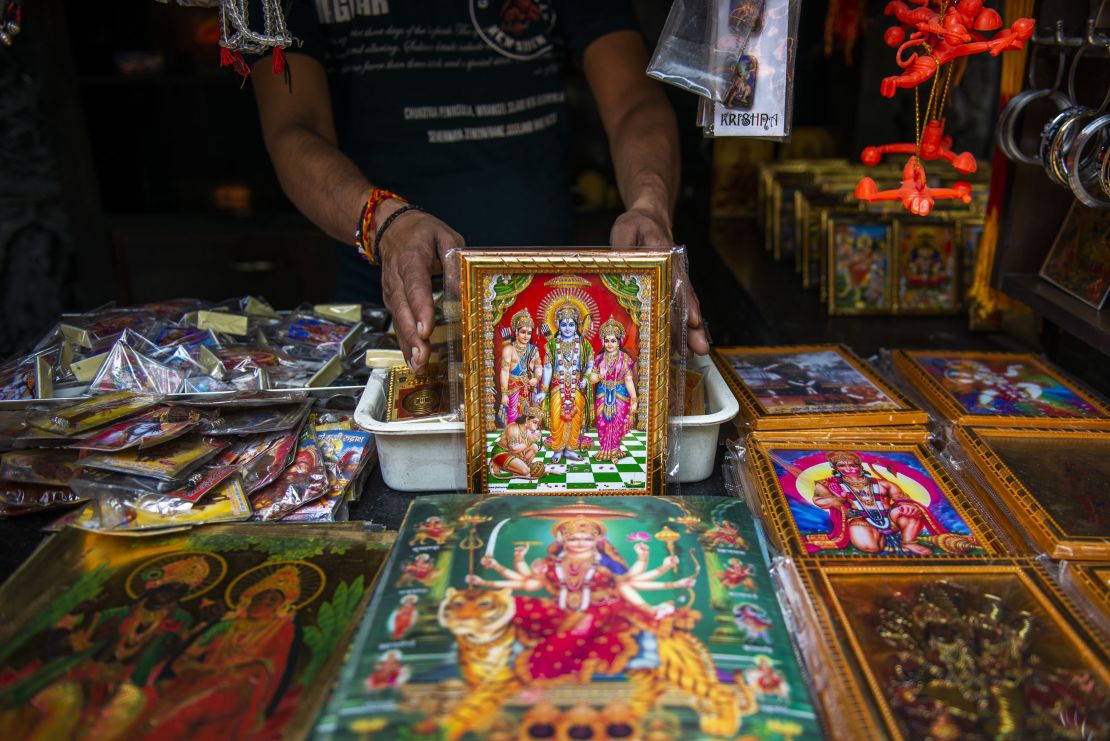 A shopkeeper is seen showing a variety of colourful frames of Lord Rama. 