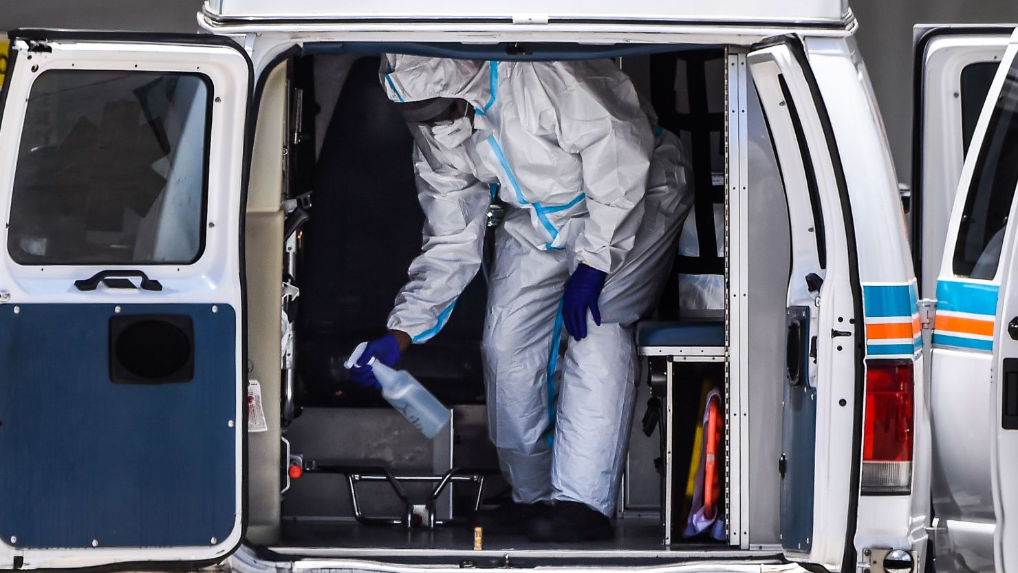 A medical worker sanitizes the ambulance after transferring a patient on a stretcher outside of Emergency at Coral Gables Hospital where coronavirus patients are treated in Coral Gables near Miami, on July 30, 2020. 