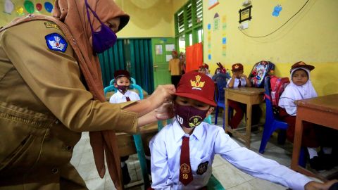 A teacher fixes a face mask for an elementary school student on July 13 in West Sumatra, Indonesia.