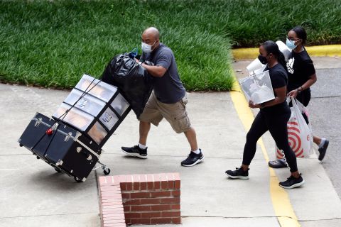 College students begin moving in for the fall semester at North Carolina State University in Raleigh on July 31. The first wave of college students returning to their dorms didn't find the typical mobs of students and parents. At NC State, the return of students was staggered over 10 days and students were greeted by socially distant volunteers donning masks and face shields.