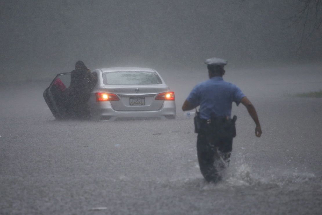 A Philadelphia police officer rushes to help a stranded driver Tuesday during Tropical Storm Isaias.