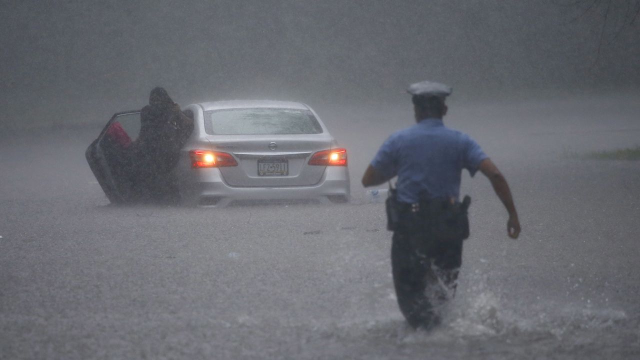 A Philadelphia police officer rushes to help a stranded driver Tuesday during Tropical Storm Isaias.