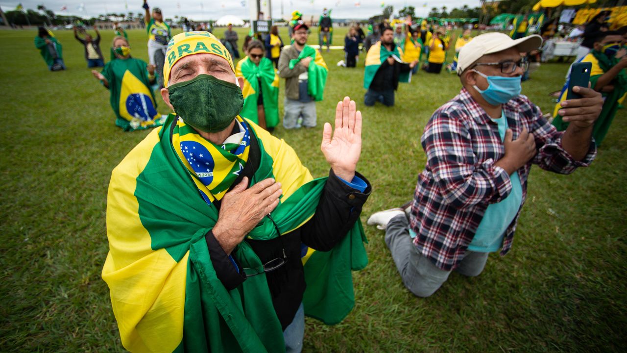 Pendukung Presiden Brasil Jair Bolsonaro berdoa selama iring-iringan mobil dan memprotes Kongres Nasional dan Mahkamah Agung atas tindakan penguncian di tengah pandemi virus corona (COVID-19) di depan Kongres Nasional pada 09 Mei 2020 di Brasilia.