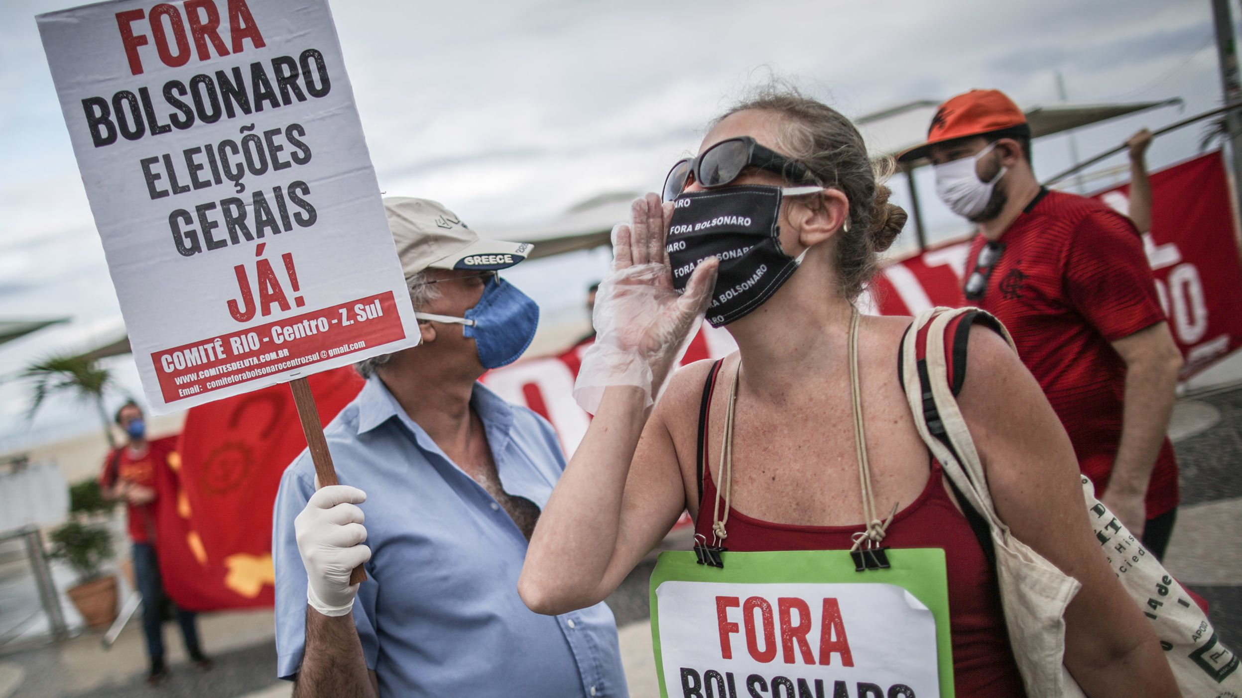 Bir gösterici "Bolsonaro'dan Defol, Genel seçimler hemen!" yazan bir pankart taşıyor. 28 Haziran 2020'de Brezilya'nın Rio de Janeiro kentindeki Copacabana plajında koronavirüs (COVID-19) salgınının ortasında Başkan Jair Bolsonaro ve Rio de Janeiro Valisi Wilson Witzel'e karşı düzenlenen miting sırasında.