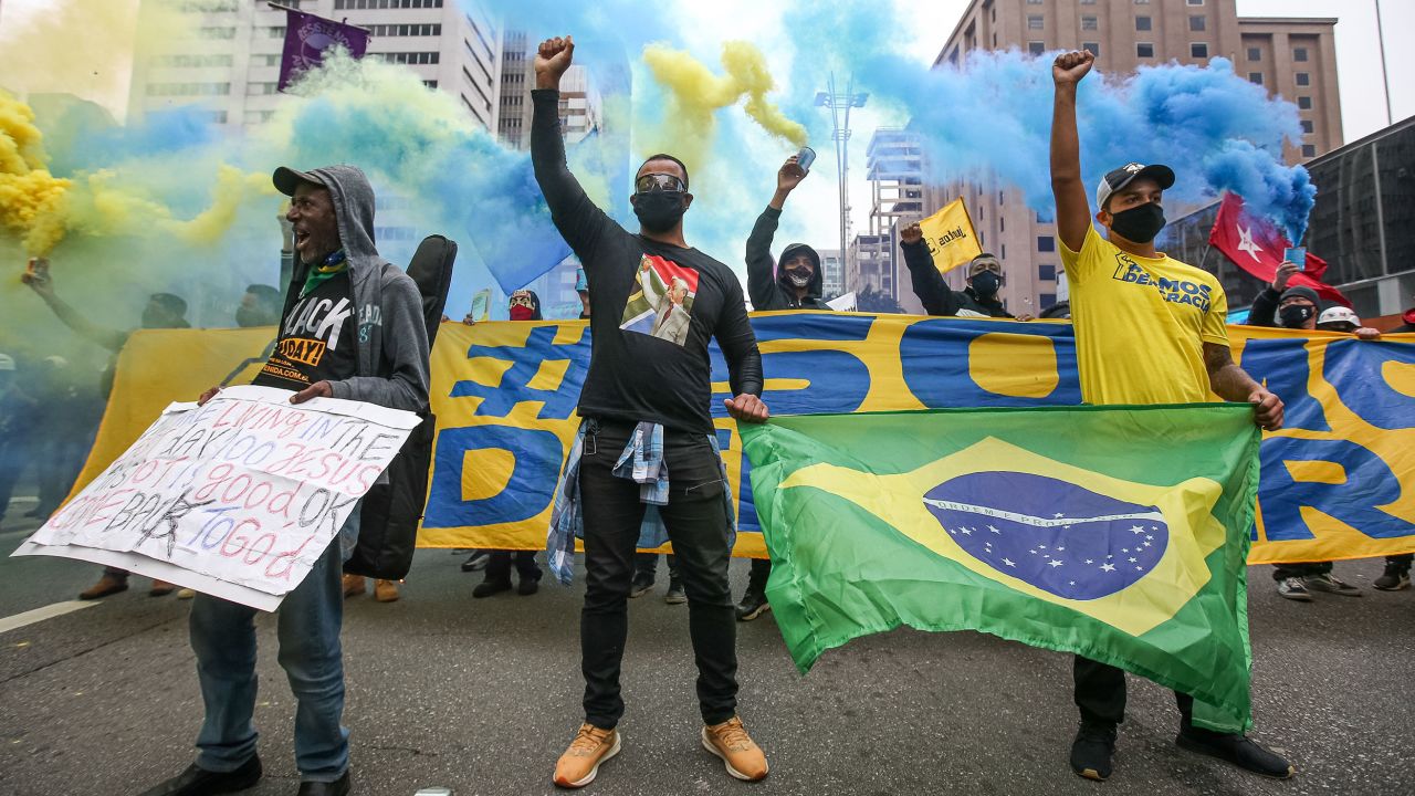 Demonstran yang mengenakan masker mengangkat tinju mereka di Paulista Avenue selama protes di tengah pandemi virus corona (COVID-19) pada 14 Juni 2020 di Sao Paulo, Brasil.
