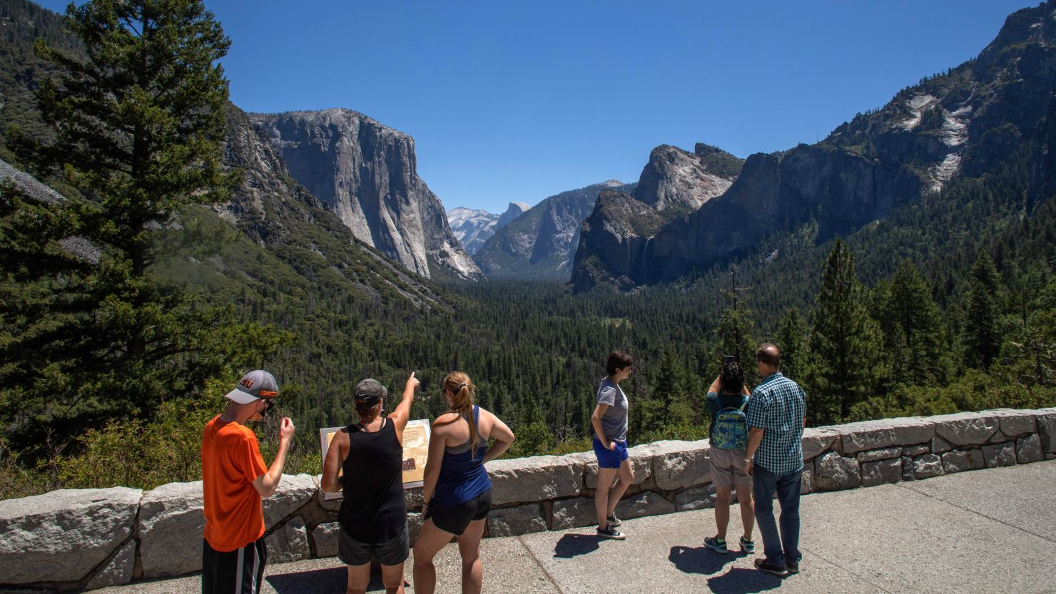 Visitors walk to the Tunnel View lookout in Yosemite Valley at Yosemite National Park, California on July 08, 2020. - After closing for 2½ months because of the coronavirus pandemic, the wildlife is taking over of areas used by the public. The park is open with limited services and facilities to those with day-use reservations, reservations for in-park lodging or camping, and wilderness or Half Dome permits. (Photo by Apu GOMES / AFP) (Photo by APU GOMES/AFP via Getty Images)