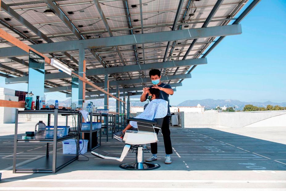 A stylist from Grey Matter LA cuts a client's hair on a rooftop parking lot in Los Angeles on August 4.