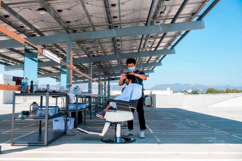 A stylist from Grey Matter LA cuts a client's hair on a rooftop parking lot in Los Angeles on August 4.
