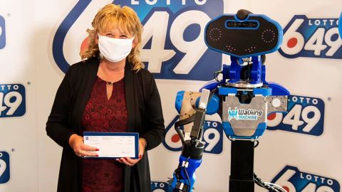 New multimillionaire, Guylaine Desjardins, stands next to the robot that presented her with her winnings. 
