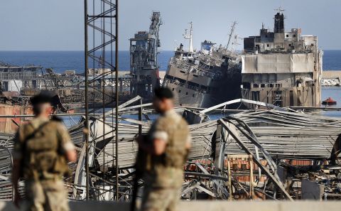 Lebanese soldiers stand guard in front of destroyed ships.