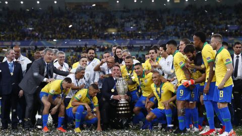     Brazil's President Jair Bolsonaro celebrates with the trophy and Brazil's players after winning the Copa America final against Peru.