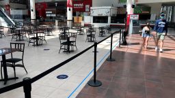 People walk past the nearly empty food court at Providence Place shopping mall, Monday, June 1, 2020, in Providence, R.I. Providence Place was opened Monday for the first time since mid-March when it was closed in response to the coronavirus crisis. The food court is open with adjusted seating to maintain social distancing. (AP Photo/Steven Senne)