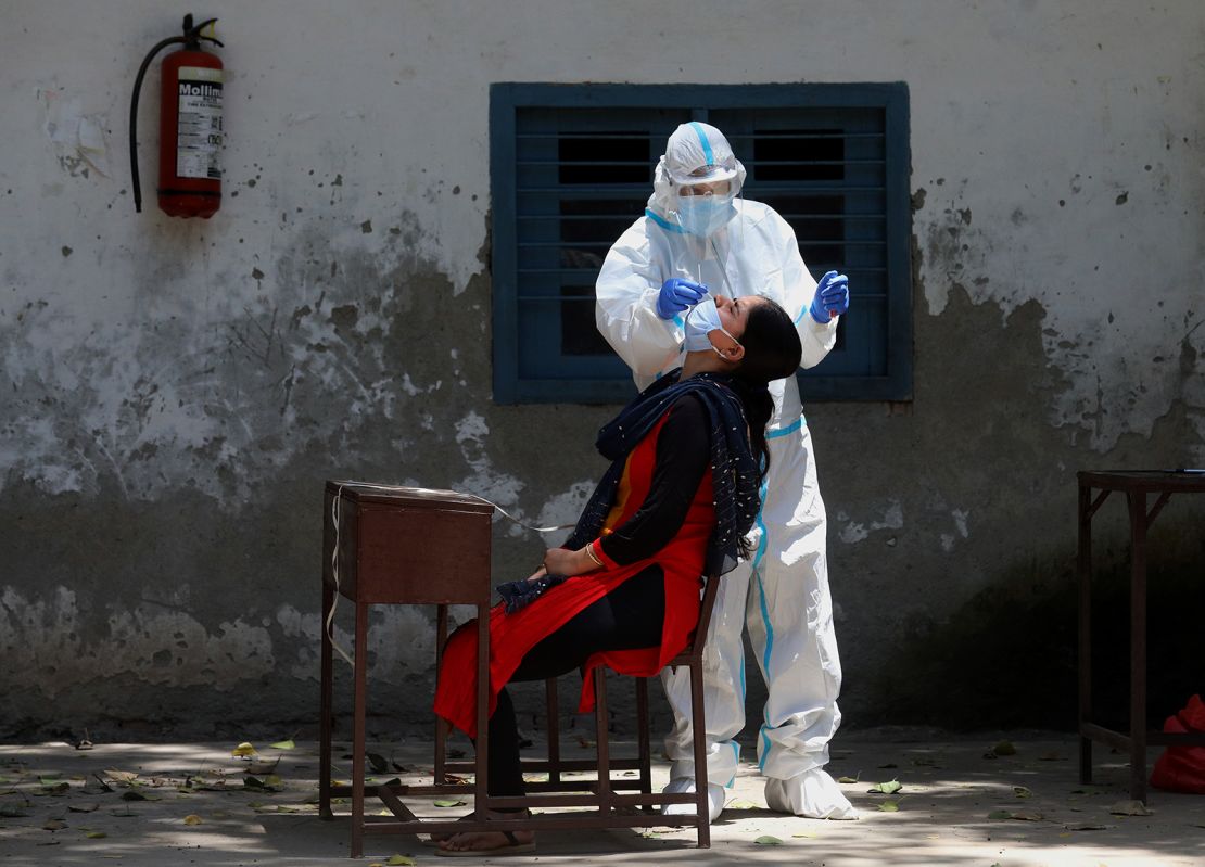 A medic wearing personal protective equipment collects a swab sample in India.