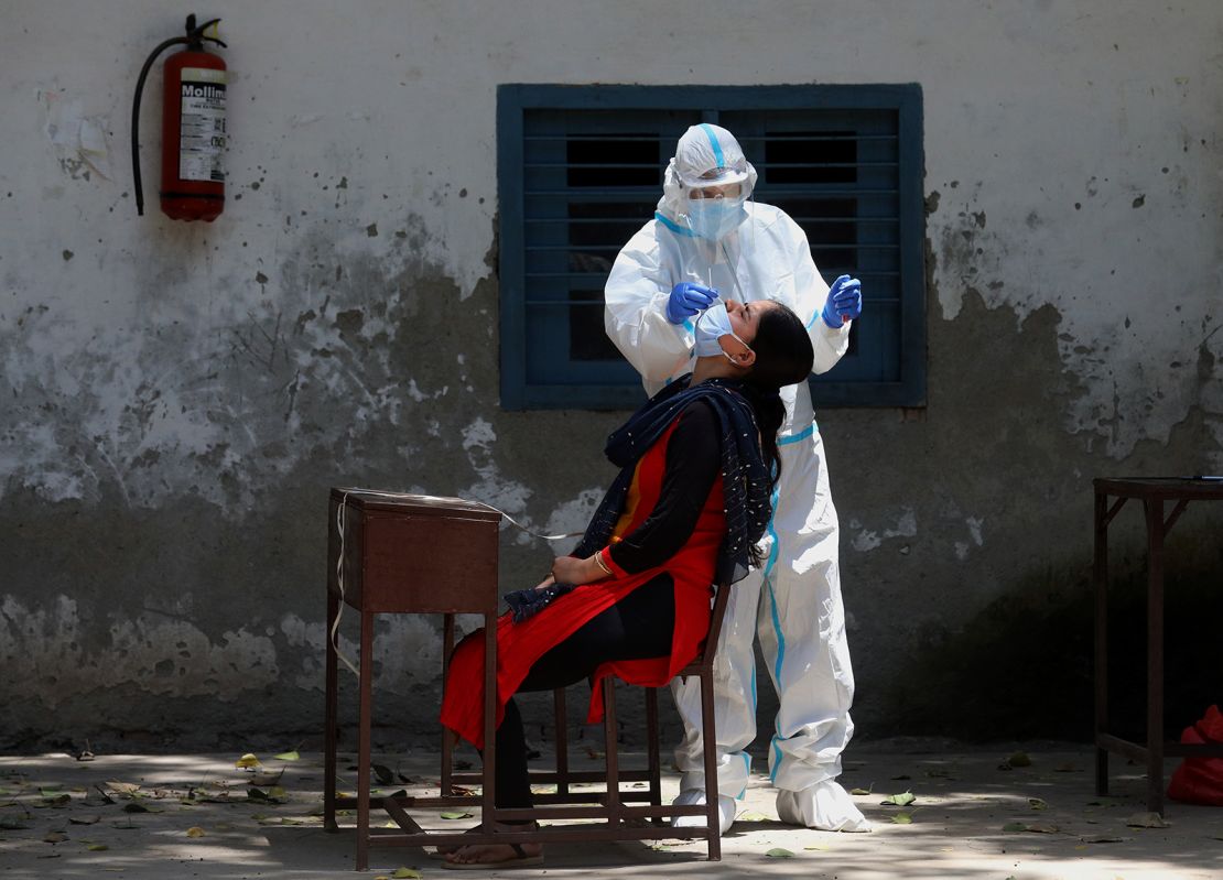 A medic wearing personal protective equipment collects a swab sample in India. 