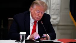 President Donald Trump looks at his phone during a roundtable with governors on the reopening of America's small businesses, in the State Dining Room of the White House, Thursday, June 18, 2020, in Washington. (AP Photo/Alex Brandon)