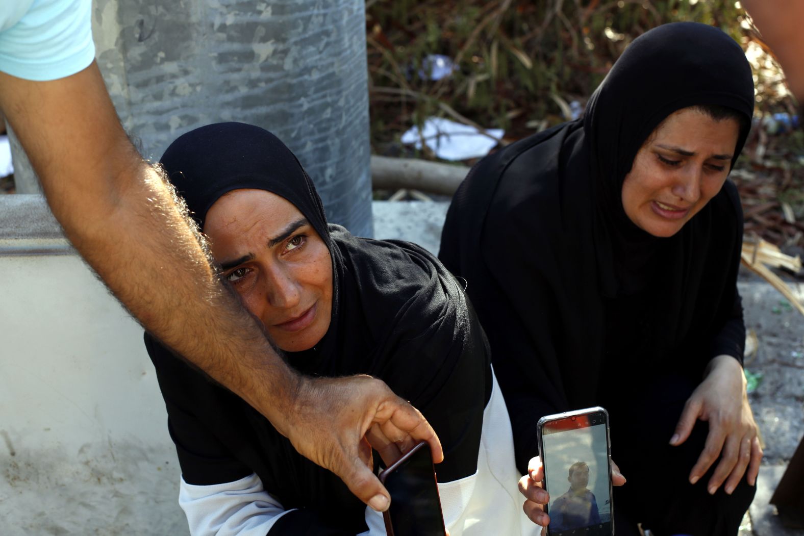 A woman and her sister-in-law show a photo of a missing man on August 7, 2020. Many people were reported missing after the explosion.