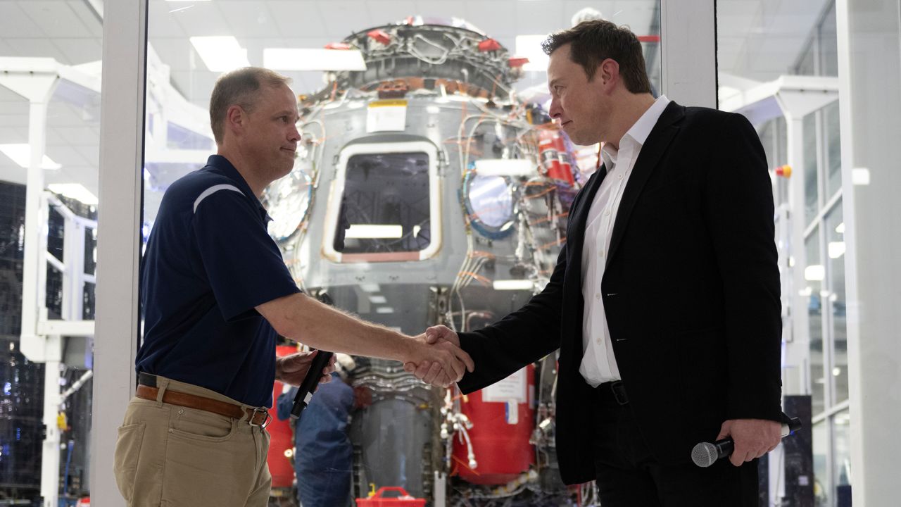 NASA administrator Jim Bridenstine and Elon Musk shake hands in front of Crew Dragon cleanroom at SpaceX Headquarters in Hawthorne, California on October 10, 2019. 