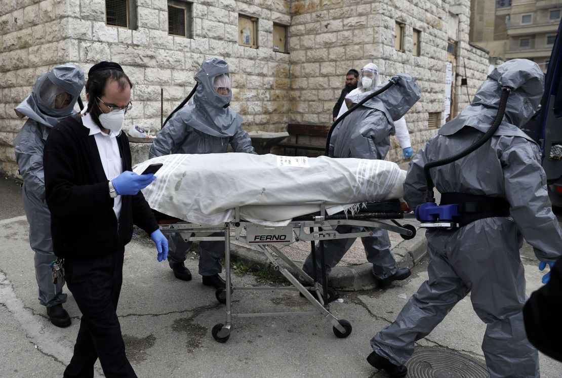 Workers at Chevra Kadisha, Israel's religious burial society, carry the body of a patient who died from complications of Covid-19 at the Shamgar Funeral Home in Jerusalem on April 1.