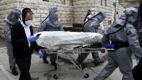 Workers at Chevra Kadisha, Israel's religious burial society,  carry the body of a patient who died from complications of Covid-19 at the Shamgar Funeral Home in Jerusalem on April 1.
