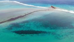 This aerial view taken on August 6, 2020 shows a large patch of leaked oil and the vessel MV Wakashio (R), belonging to a Japanese company but Panamanian-flagged, that ran aground near Blue Bay Marine Park off the coast of south-east Mauritius. - France on August 8, 2020 dispatched aircraft and technical advisers from Reunion to Mauritius after the prime minister appealed for urgent assistance to contain a worsening oil spill polluting the island nation's famed reefs, lagoons and oceans. Rough seas have hampered efforts to stop fuel leaking from the bulk carrier MV Wakashio, which ran aground two weeks ago, and is staining pristine waters in an ecologically protected marine area off the south-east coast. (Photo by STRINGER / AFP) (Photo by STRINGER/AFP via Getty Images)