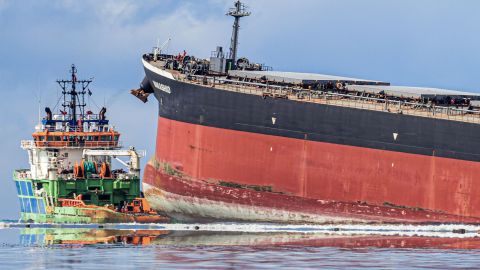Workers look from a ship towards the vessel MV Wakashio that ran aground.