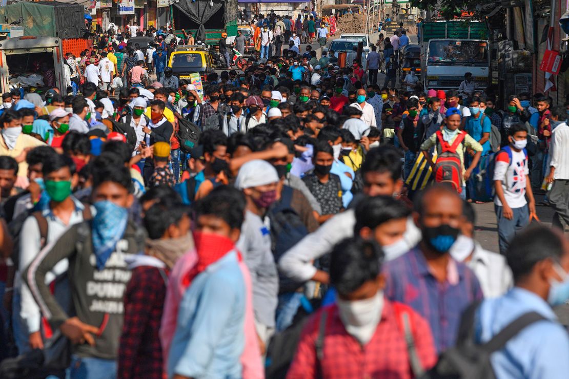 Migrant workers gather outside Dharavi slums to wait for a bus to take them to board a special train back home during a nationwide lockdown in Mumbai on May 12, 2020. 