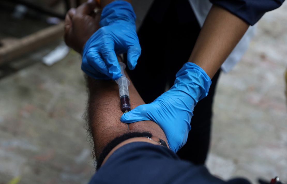 A medical personnel collects a blood sample from a man in India.