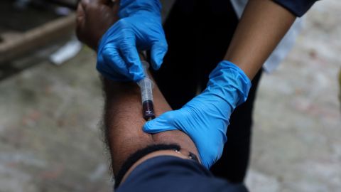 A medical personnel collects a blood sample from a man in India. 