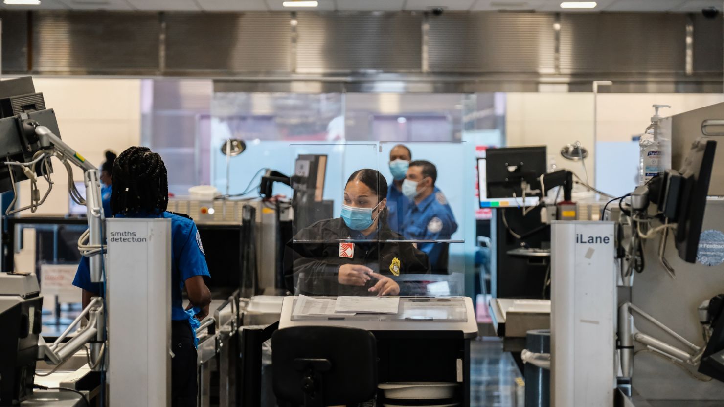 ARLINGTON, VA - JULY 22: TSA agents work at a security checkpoint at the Ronald Reagan National Airport on July 22, 2020 in Arlington, Virginia. During the COVID-19 pandemic, all employees and passengers are required to wear facemasks while onboard a Delta plane. (Photo by Michael A. McCoy/Getty Images)