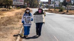 TOPSHOT - Zimbabwean novelist Tsitsi Dangarembga (L) and a colleague Julie Barnes hold placards during an anti-corruption protest march along Borrowdale road, on July 31, 2020 in Harare. - Police in Zimbabwe arrested on July 31, 2020 internationally-aclaimed novelist Tsitsi Dangarembga as they enforced a ban on protests coinciding with the anniversary of President Emmerson Mnangagwa's election. Dangarembga, 61, was bundled into a police truck as she demonstrated in the upmarket Harare suburb of Borrowdale alongside another protester. (Photo by ZINYANGE AUNTONY / AFP) (Photo by ZINYANGE AUNTONY/AFP via Getty Images)