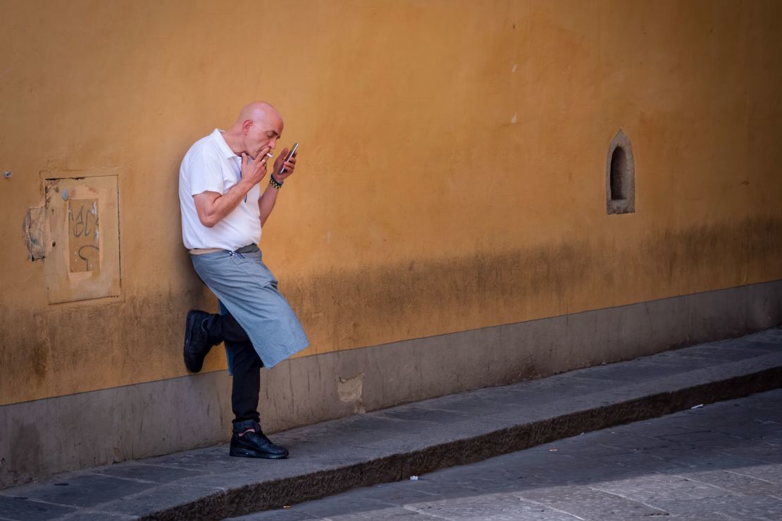 A man pauses for a cigarette break near a wine window