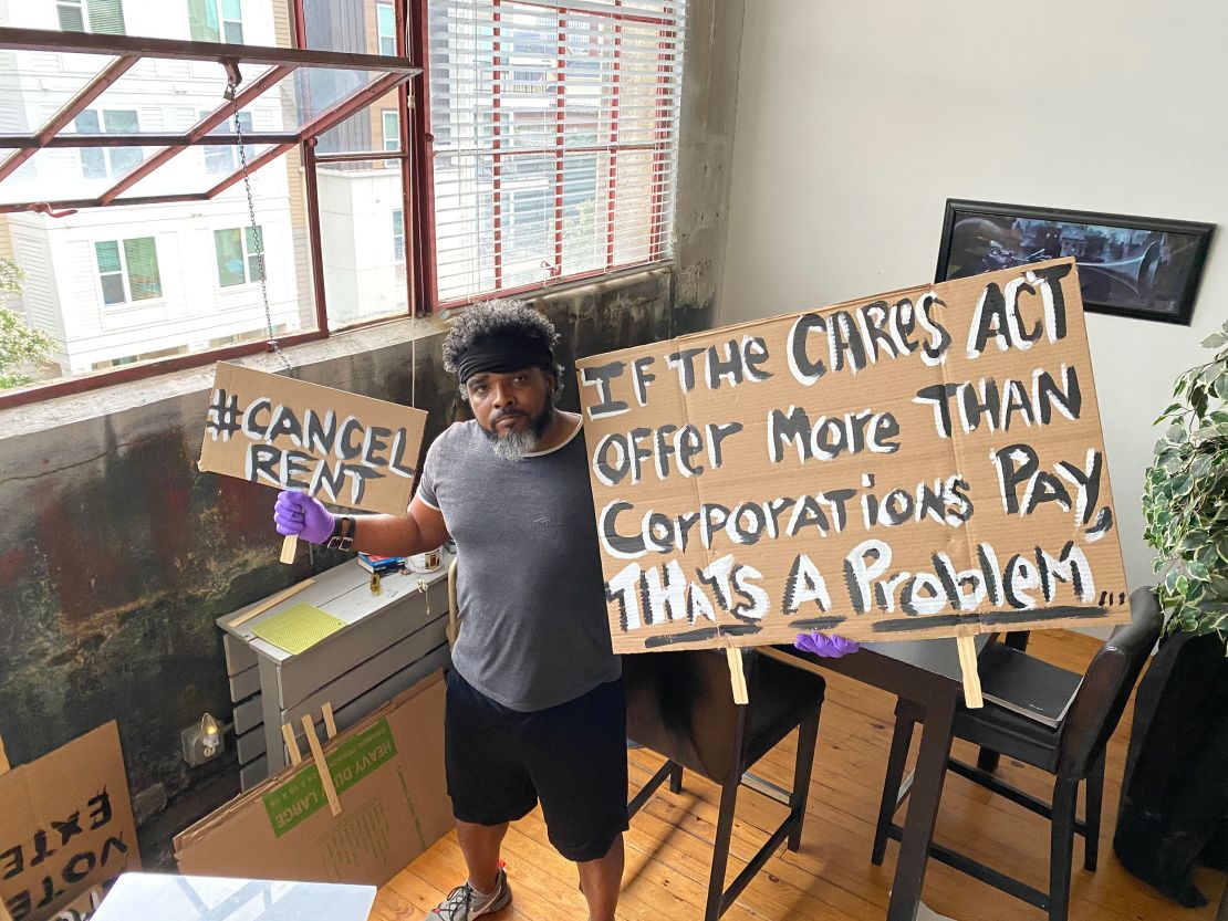 Furloughed airport bartender Robert Davis, 51, stands in his downtown Atlanta apartment on Aug. 10, 2020 with protest signs he's planning to use at a protest in support of the HEROES Act.