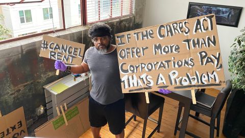 Furloughed airport bartender Robert Davis, 51, stands in his downtown Atlanta apartment on Aug. 10, 2020 with protest signs he's planning to use at a protest in support of the HEROES Act.
