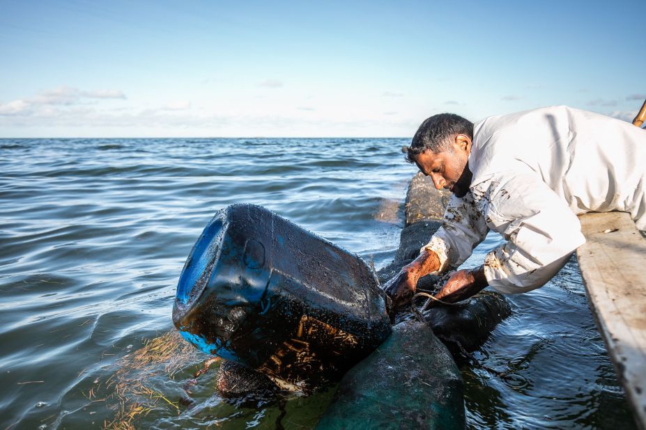 A fisherman places handmade oil barriers into the sea on August 11.