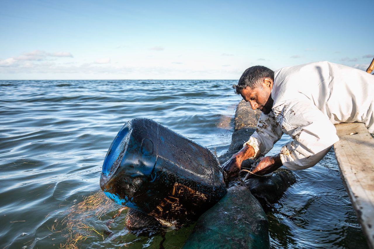 A fisherman places handmade oil barriers into the sea on August 11.