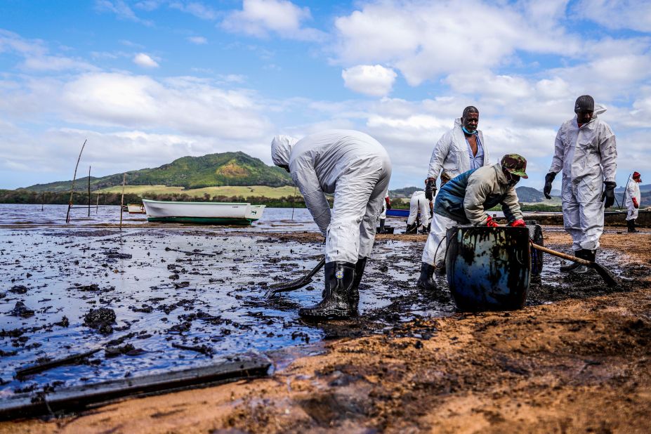 People scoop oil near Blue Bay Marine Park on August 9.