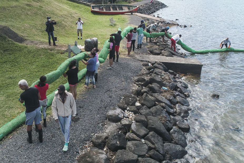 Volunteers carry a handmade oil barrier on August 10.