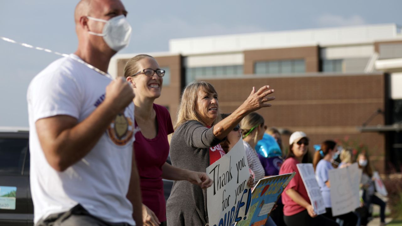 Supporters of the Cherokee County School District's decision to reopen schools cheer on faculty arriving to the district's headquarters in Canton, Georgia. 