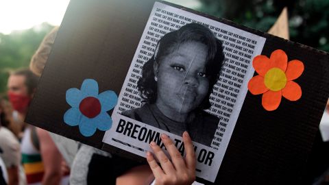 A demonstrator holds a sign with the image of Breonna Taylor, a Black woman who was fatally shot by Louisville Metro Police Department officers. 