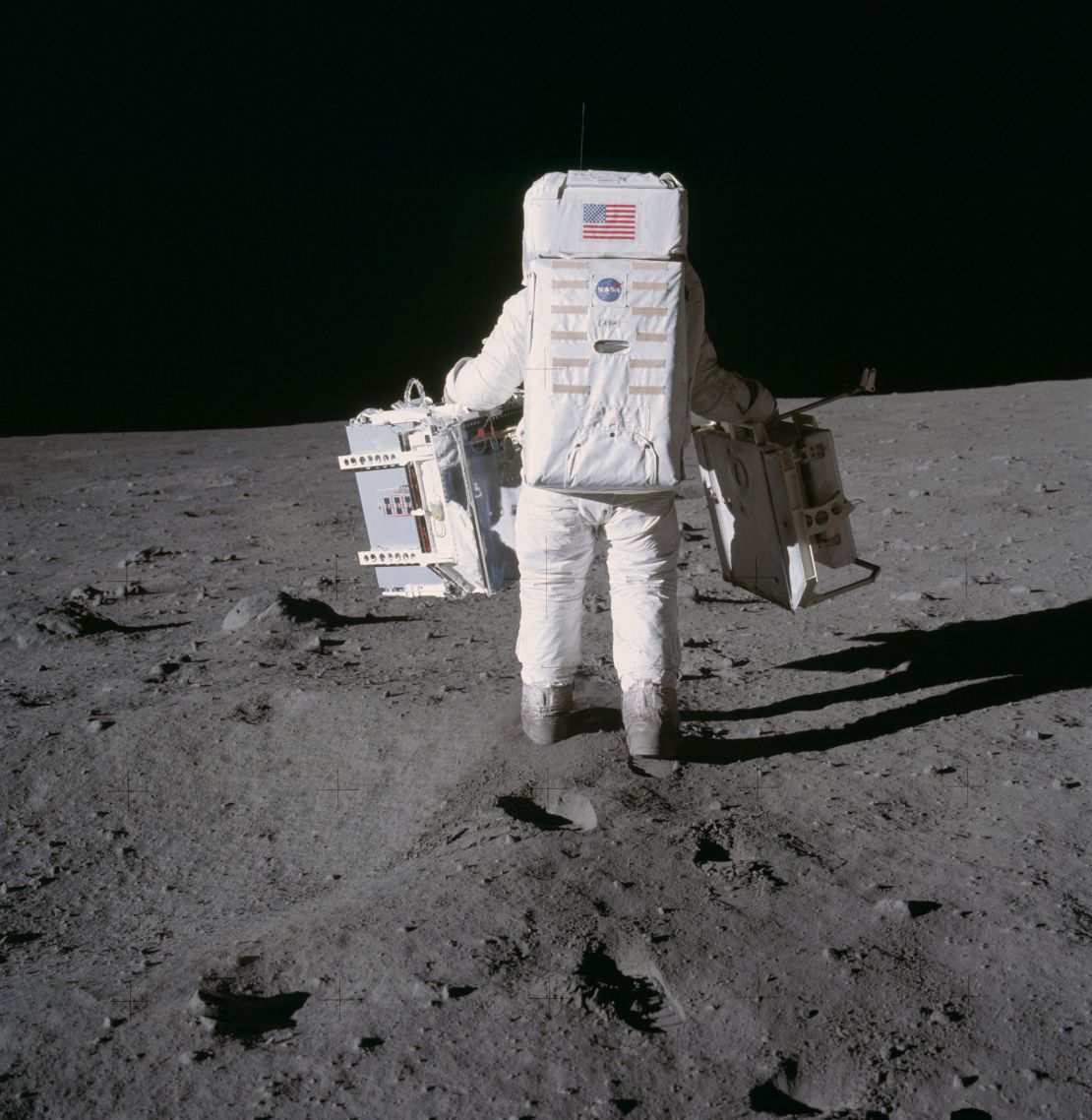 Astronaut Buzz Aldrin placed two experiments on the moon's during the Apollo 11 extravehicular activity in 1969. In his left hand is a seismic experiment, and in his right is a laser-reflecting panel.