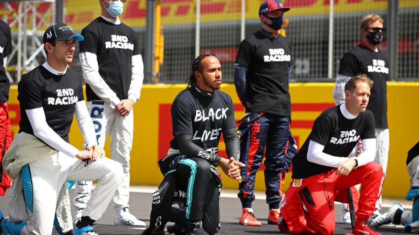 TOPSHOT - Mercedes' British driver Lewis Hamilton (C) and fellow drivers make a statement on the track as they 'take a knee' in support of the Black Lives Matter movement, prior to the start of the Formula One British Grand Prix at the Silverstone motor racing circuit in Silverstone, central England on August 2, 2020. (Photo by Bryn Lennon / POOL / AFP) (Photo by BRYN LENNON/POOL/AFP via Getty Images)