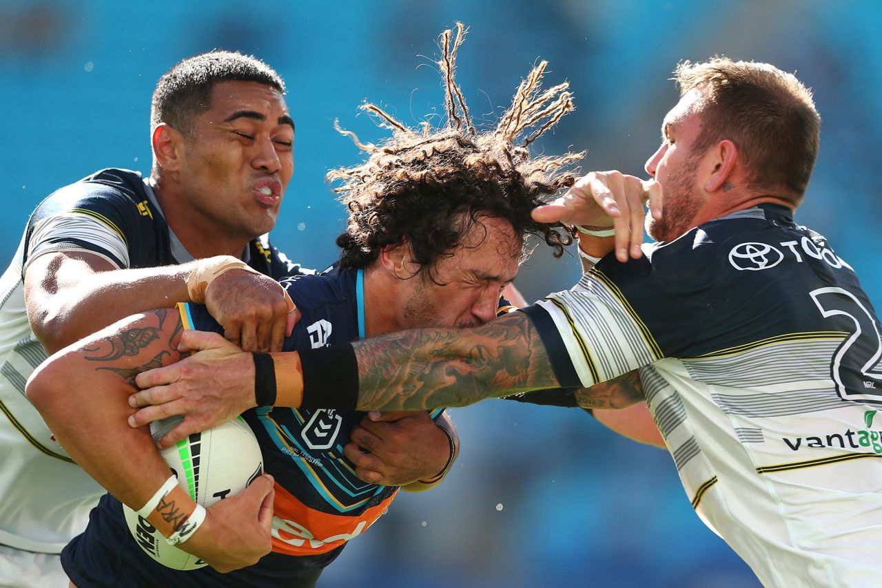 Kevin Proctor of the Gold Coast Titans is tackled by two North Queensland Cowboys during a National Rugby League match in Gold Coast, Australia, on Sunday, August 9.