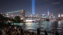 People on the shore watch The Tribute in Light shining into the sky over Manhattan's skyline on September 11, 2019 in New York. - The art installation of 88 searchlights is marking the 18th anniversary of the 911 attacks (Photo by Johannes EISELE / AFP) (Photo by JOHANNES EISELE/AFP via Getty Images)