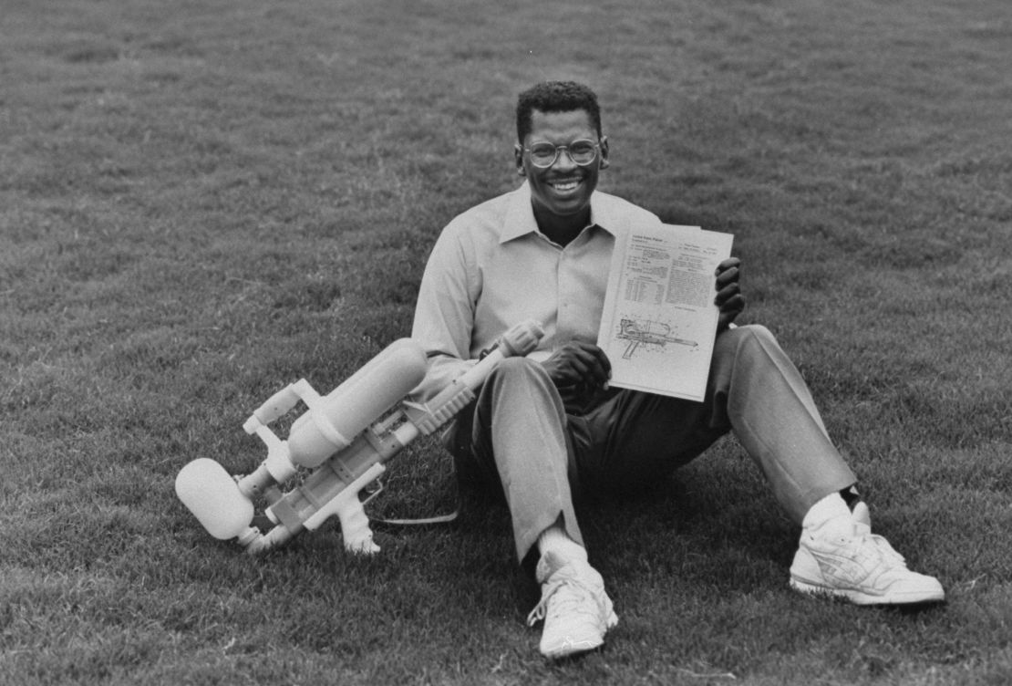 Lonnie Johnson, inventor of Super Soaker a large plastic pump-action water gun, holding his invention & its US patent while sitting on grass outside his home.  (Photo by Thomas S. England/The LIFE Images Collection via Getty Images/Getty Images)