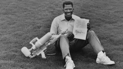 Lonnie Johnson, inventor of Super Soaker a large plastic pump-action water gun, holding his invention & its US patent while sitting on grass outside his home.  (Photo by Thomas S. England/The LIFE Images Collection via Getty Images/Getty Images)