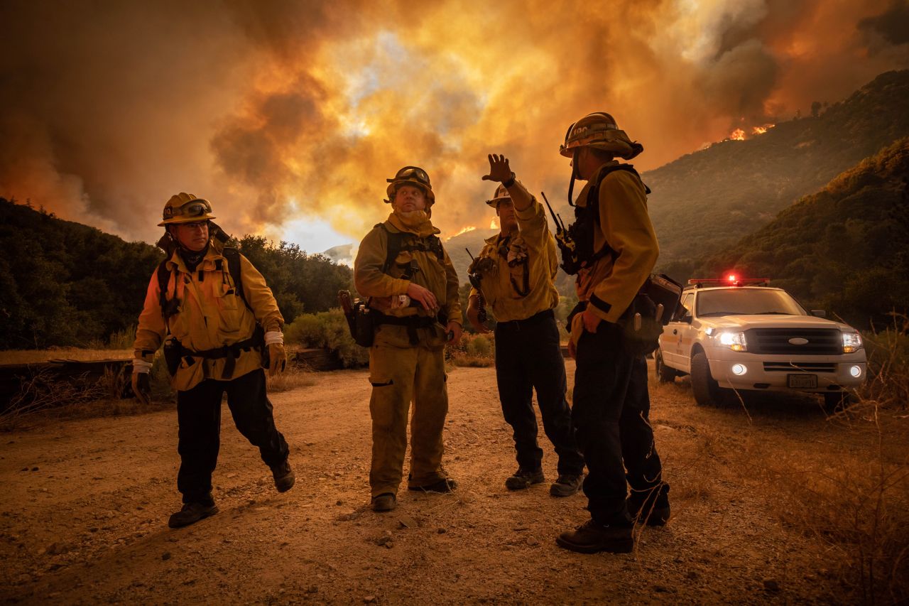Firefighters make an escape plan as the Lake Fire burns a hillside on August 12, 2020.