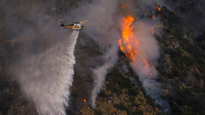 A helicopter makes a water drop over the Ranch Fire, Thursday, Aug. 13, 2020, in Azusa, Calif. Heat wave conditions were making difficult work for fire crews battling brush fires and wildfires across Southern California. (AP Photo/Marcio Jose Sanchez)