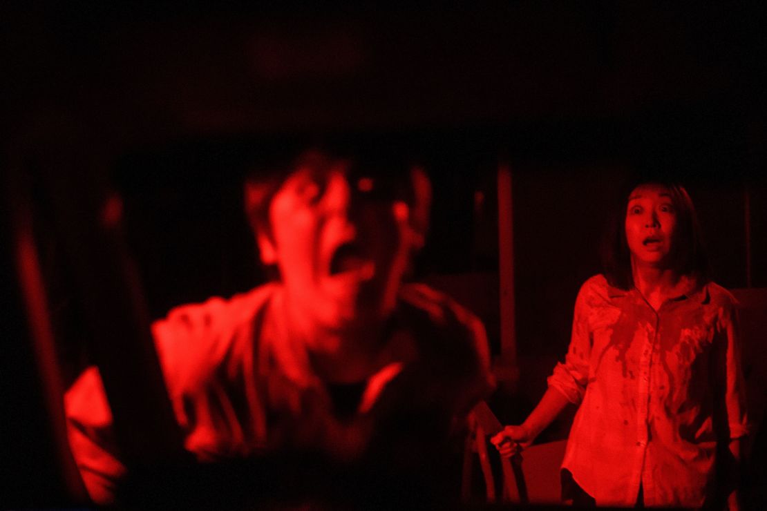 Actors give a red-lighted haunting performance at the drive-in haunted house in Tokyo. 