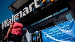A woman wearing a facemask walks past a sign informing customers that face coverings are required in front of a Walmart store in Washington, DC on July 15, 2020. - Walmart will require shoppers to wear face masks starting next week, the US retail giant announced on July 15, joining an increasing number of businesses in mandating the protection amid the latest spike in coronavirus cases. (Photo by Andrew Caballero-Reynolds/AFP/Getty Images)