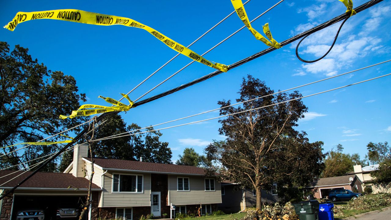 Caution tape is wrapped around a low downed power line that stretches over a roadway, Thursday, Aug. 13, 2020, after a derecho in Cedar Rapids, Iowa.